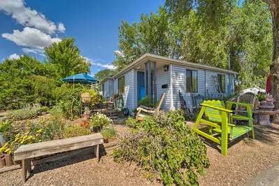 a tiny house in a garden with a bench at Walk to Old Town Arvada - 1940 Vintage Bungalow! in Arvada