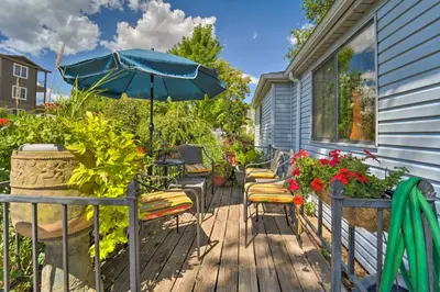 a deck with chairs and an umbrella and flowers at Walk to Old Town Arvada - 1940 Vintage Bungalow! in Arvada