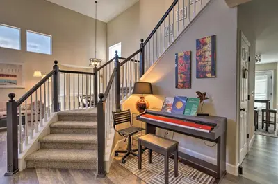 a staircase with a piano in a living room at Spacious Parkview Home Near Denver with Game Room in Thornton