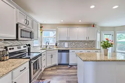 a kitchen with white cabinets and granite counter tops at Spacious Parkview Home Near Denver with Game Room in Thornton