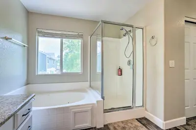 a bathroom with a tub and a shower with a window at Spacious Parkview Home Near Denver with Game Room in Thornton