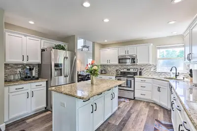 a kitchen with white cabinets and marble counter tops at Spacious Parkview Home Near Denver with Game Room in Thornton