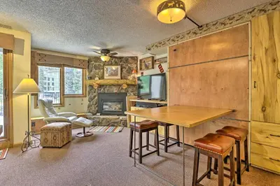 a living room with a table and a fireplace at Ski-InandSki-Out Studio at Winter Park Base! in Winter Park