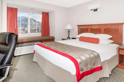 a hotel room with a bed and a chair and a window at Ramada by Wyndham Frisco in Frisco