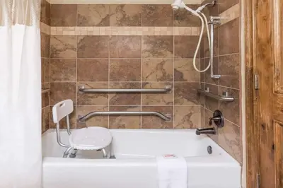 a bathroom with a bath tub and a chair at Ramada by Wyndham Frisco in Frisco