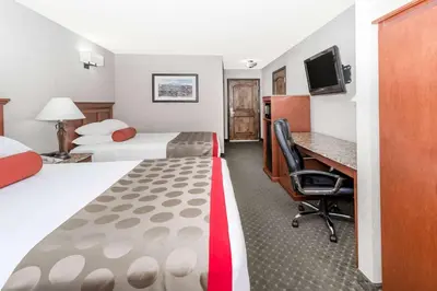 a hotel room with two beds and a desk at Ramada by Wyndham Frisco in Frisco