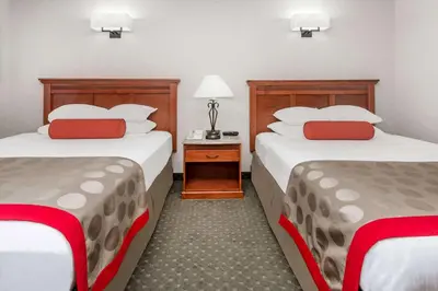 a hotel room with two beds with red pillows at Ramada by Wyndham Frisco in Frisco