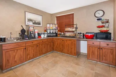 a kitchen with wooden cabinets and a counter top at Ramada by Wyndham Frisco in Frisco
