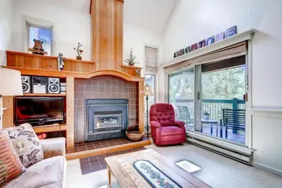 a living room with a fireplace and a red chair at Soda Springs 1 Bedroom Townhome in Keystone