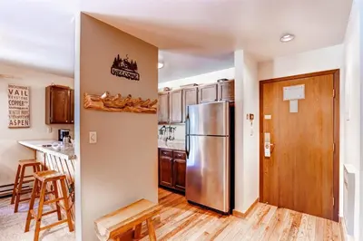 a kitchen with a stainless steel refrigerator and wooden floors at 1 Bedroom Condo In Keystone - West Keystone in Keystone
