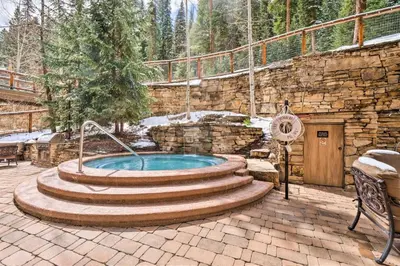 a hot tub in a patio with a stone wall at The Timbers In River Run 2 Bedroom Condo in Dillon