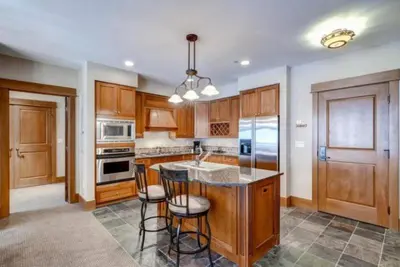 a kitchen with wooden cabinets and a island with bar stools at The Timbers In River Run 2 Bedroom Condo in Dillon
