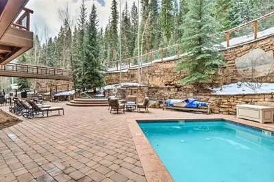 a backyard with a swimming pool and a stone wall at The Timbers In River Run 2 Bedroom Condo in Dillon