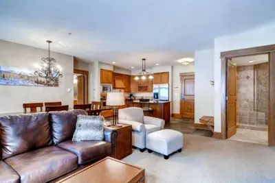 a living room with a leather couch and a kitchen at The Timbers In River Run 2 Bedroom Condo in Dillon