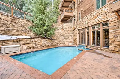 a swimming pool in front of a brick building at 2 Bedroom Ski-In, Ski-Out Condo At The Timbers in Keystone