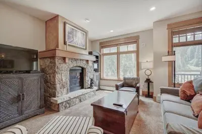 a living room with a stone fireplace and a tv at Lone Eagle 2 Bedroom Condo in Dillon