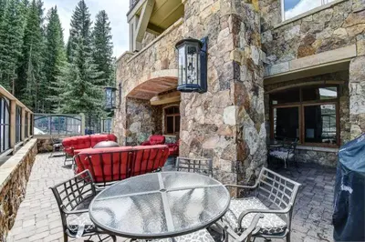 a patio with a table and chairs and a stone building at Lone Eagle 2 Bedroom Condo in Dillon