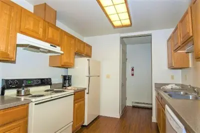 a kitchen with wooden cabinets and a white refrigerator at Twin Rivers By Alderwood Colorado Management in Fraser