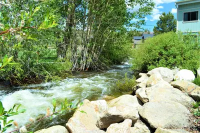 a river with rocks and trees and a house at Twin Rivers By Alderwood Colorado Management in Fraser
