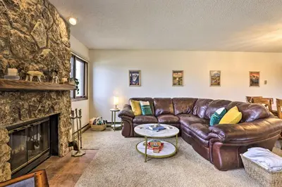 a living room with a leather couch and a fireplace at Mtn View Granby Condo with In-Unit Hot Tub! in Granby