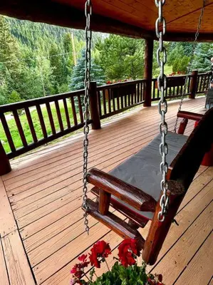 a swing on a porch with a bench and flowers at Classic Log Cabin near Rocky Mountain National Park and near Skiing in Lyons