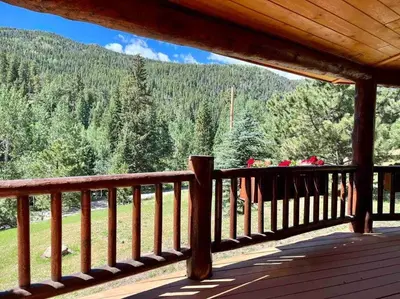 a wooden deck with a table with flowers on it at Classic Log Cabin near Rocky Mountain National Park and near Skiing in Lyons