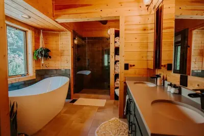 a bathroom with a tub and two sinks and a shower at Classic Log Cabin near Rocky Mountain National Park and near Skiing in Lyons