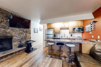 a kitchen with a bar with stools and a fireplace at Hi Country 11-13 in Winter Park