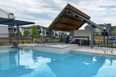 a swimming pool with a patio with chairs and a table at Modern Farmhouse Townhome - Great Central Location in Fort Collins