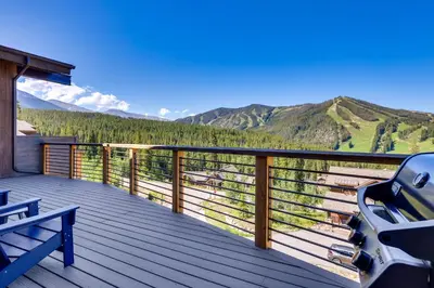 a deck with a bench and mountains in the background at Mountain Home with Hot Tub, Near WP Resort! in Winter Park