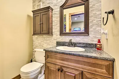 a bathroom with a toilet and a sink and a mirror at Game Room and Hot Tub Luxe Grand Lake Retreat! in Grand Lake