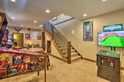 a living room with a staircase and a large screen at Game Room and Hot Tub Luxe Grand Lake Retreat! in Grand Lake