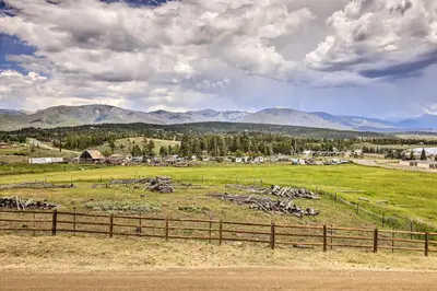 a field with a fence and mountains in the background at Game Room and Hot Tub Luxe Grand Lake Retreat! in Grand Lake