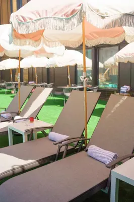 a row of lounge chairs with umbrellas in a pool at The Boulder Broker in Boulder