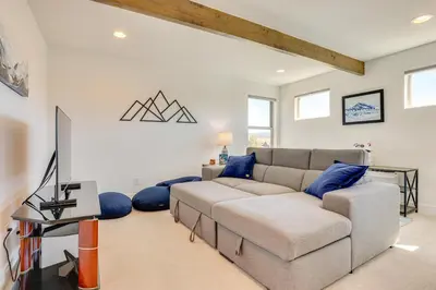 a living room with a couch and blue pillows at Furnished Deck and Hot Tub Chic Granby Home! in Granby