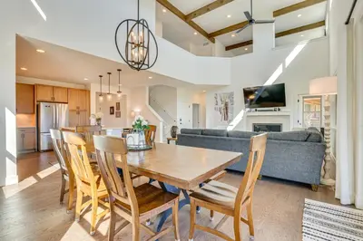 a kitchen and living room with a wooden table and chairs at Furnished Deck and Hot Tub Chic Granby Home! in Granby