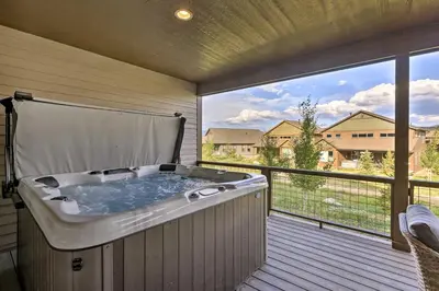 a hot tub on a deck with a large window at Furnished Deck and Hot Tub Chic Granby Home! in Granby
