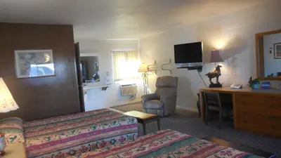 a hotel room with two beds and a desk and a television at Budget Host Exit 254 Inn in Loveland