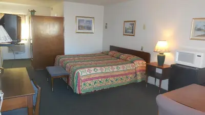 a hotel room with a bed and a table at Budget Host Exit 254 Inn in Loveland
