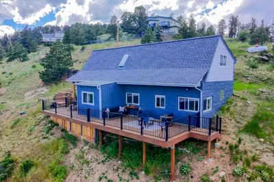 a blue house with a deck on a hill at The View at Mountain Retreat By Red Rocks and Golden in Evergreen