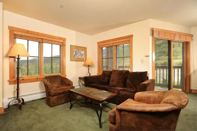 a living room with a couch and chairs and windows at Expedition Station Condos by Vail Resorts in Keystone