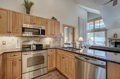 a kitchen with wooden cabinets and stainless steel appliances at Expedition Station Condos by Vail Resorts in Keystone