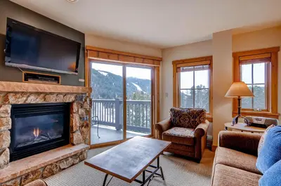a living room with a fireplace and a tv at Expedition Station Condos by Vail Resorts in Keystone