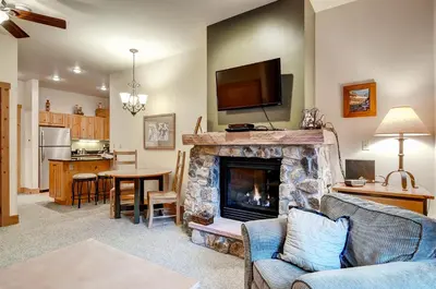 a living room with a fireplace with a tv above it at Expedition Station Condos by Vail Resorts in Keystone