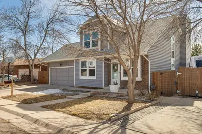 a house with a tree in front of a driveway at 6 Mi to Dtwn Arvada Home with Hot Tub and Yard in Arvada