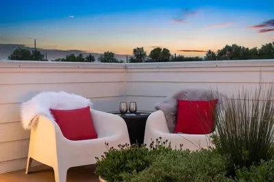 two white chairs with red pillows on a patio at Sleek Home near Old Town with Rooftop Hot Tub & Mtn Views in Fort Collins