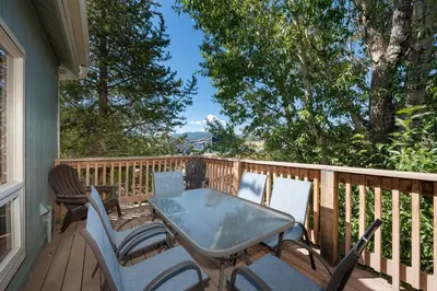 a patio with a table and chairs on a deck at Twin Rivers Vasquez 3 by Stay Winter Park in Fraser