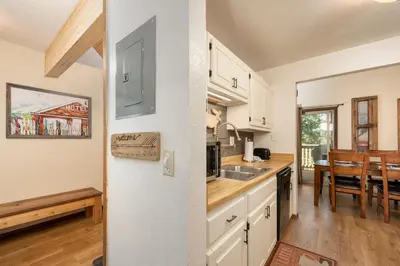 a kitchen with white cabinets and a dining room at Twin Rivers Vasquez 3 by Stay Winter Park in Fraser