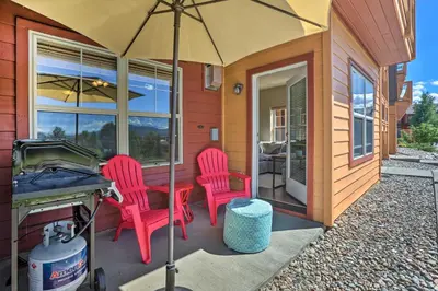 a patio with two red chairs and a grill at Condo Near Winter Park Resort and Steps From Shuttle in Fraser