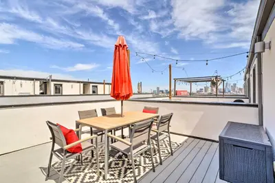 a table and chairs on a balcony with an umbrella at City Skyline Views Upscale Denver Townhome in Denver